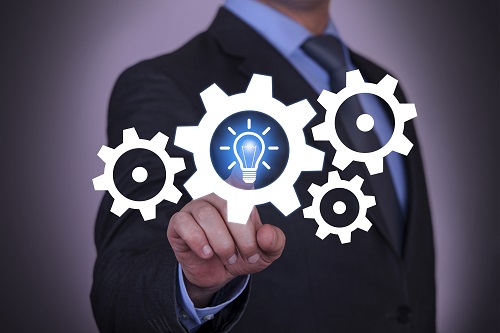 Image of the hand of a businessman touching a light bulb in an idea and gear cog