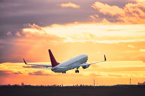 An airplane takes off into an orange sunset