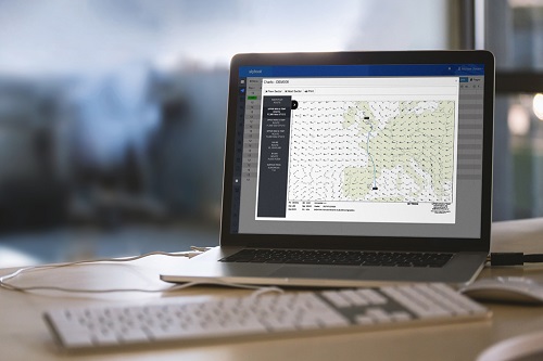 Weather data and route plots shown together in skybook displayed on a laptop. The laptop is on a desk along with a keyboard and mouse.