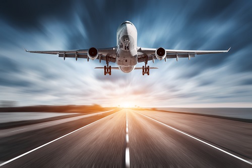 Passenger Aircraft departing a runway with a blue sky and sunset in the background.