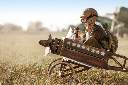 Historical image of a young boy in a wooden airplane toy