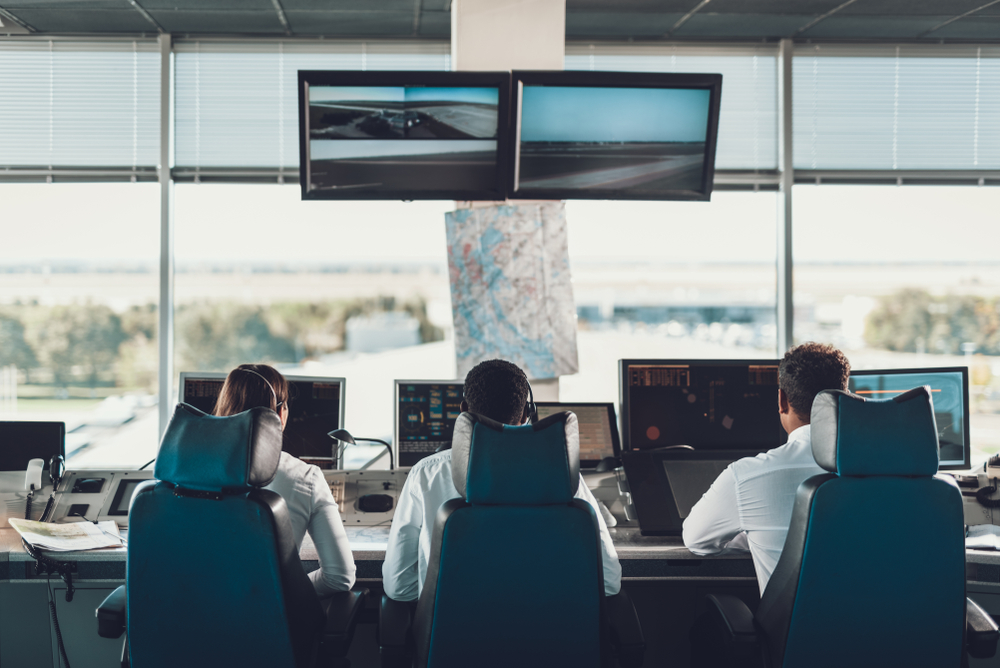 A female and two male flight dispatchers are sat in front of monitors tracking flights and weather conditions.