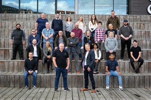 This is an image of the Bytron team pictured at The Deep in Hull. The managers are at the forefront of the image and the rest of the team are stood or sitting behind them.